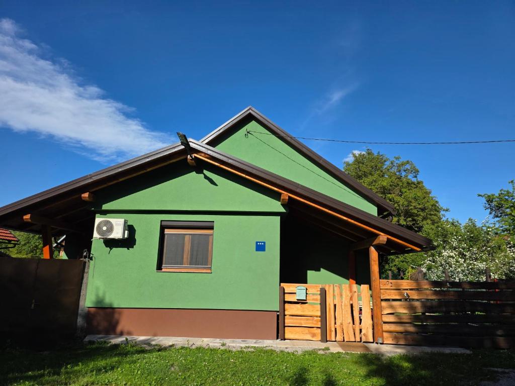 a green house with a fence in front of it at Kod bake in Oštarije