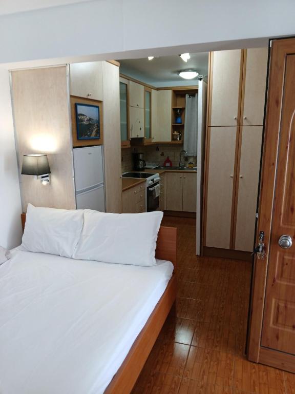 a bedroom with a white bed and a kitchen at Demetrius's Penthouse in Chalkida