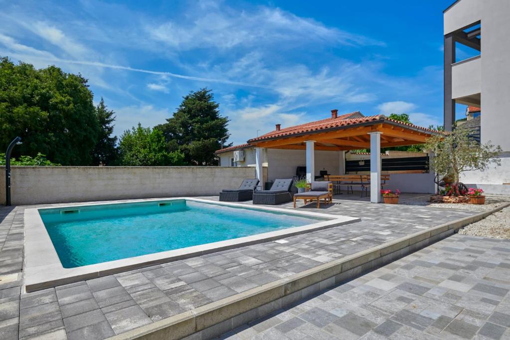 a swimming pool in a backyard with a house at Small stone house in Ližnjan