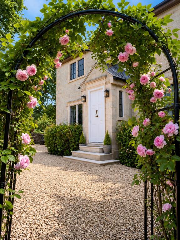 a gate with pink roses in front of a house at The little Hotel-luxury home in Motcombe