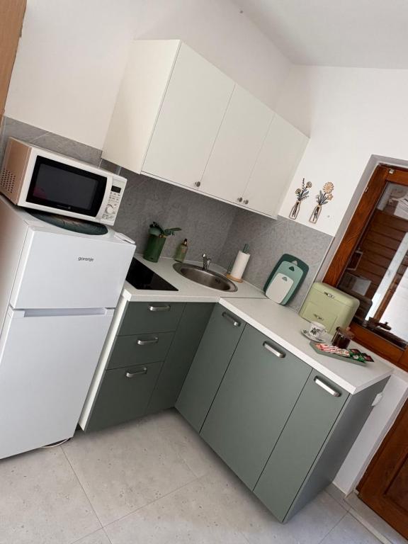 a kitchen with a white refrigerator and a microwave at Apartmani Primorski kutak in Jadranovo