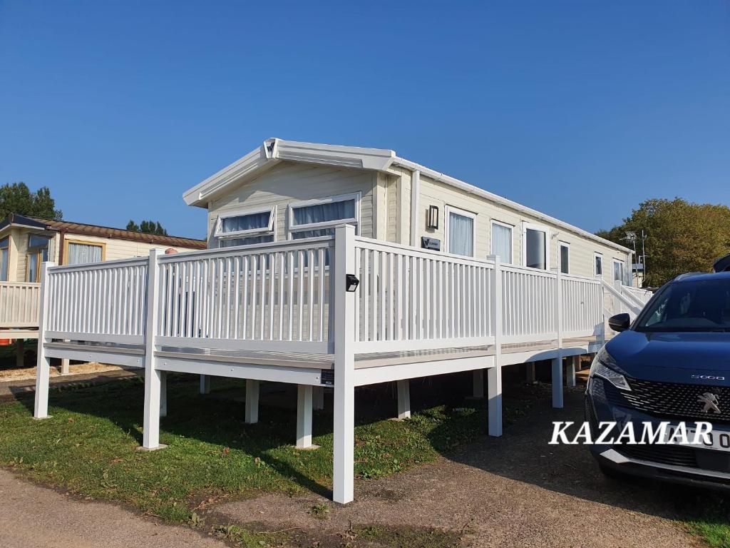 a mobile home with a white deck and a car at Kazamar in East Mersea