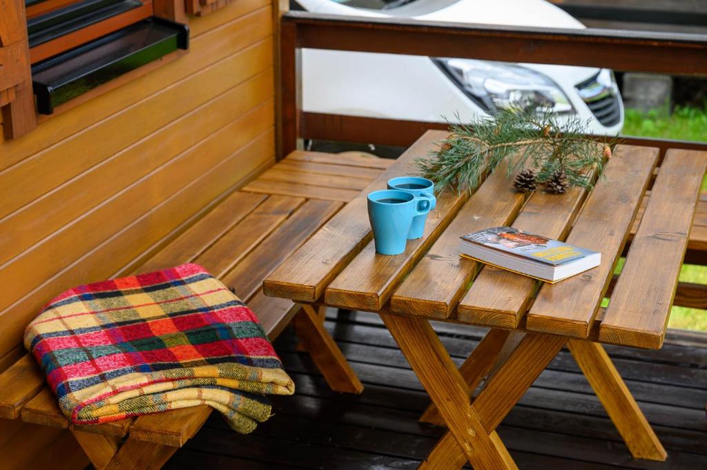 a wooden picnic table with a blanket and a book at Domki letniskowe Nevada in Darlowko