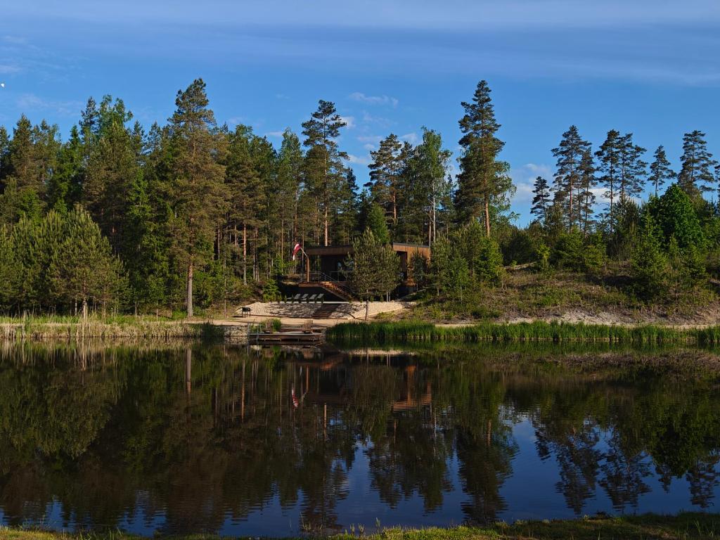 a house in the woods next to a lake at AVOTUPJi in Plānupe