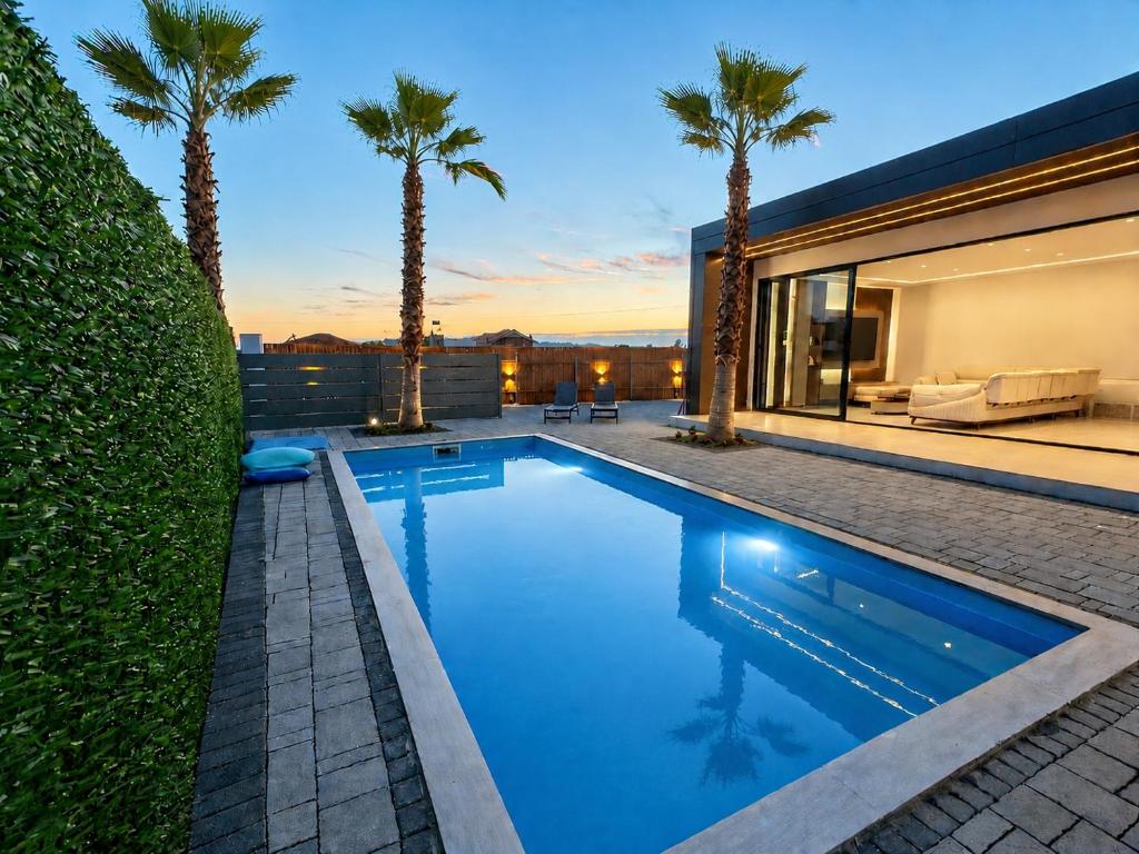 a swimming pool in the backyard of a house with palm trees at Lakeside Palms in Tirana