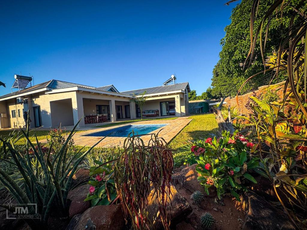 a house with a yard with flowers and plants at Judith & Sylvester Hideaway in Victoria Falls