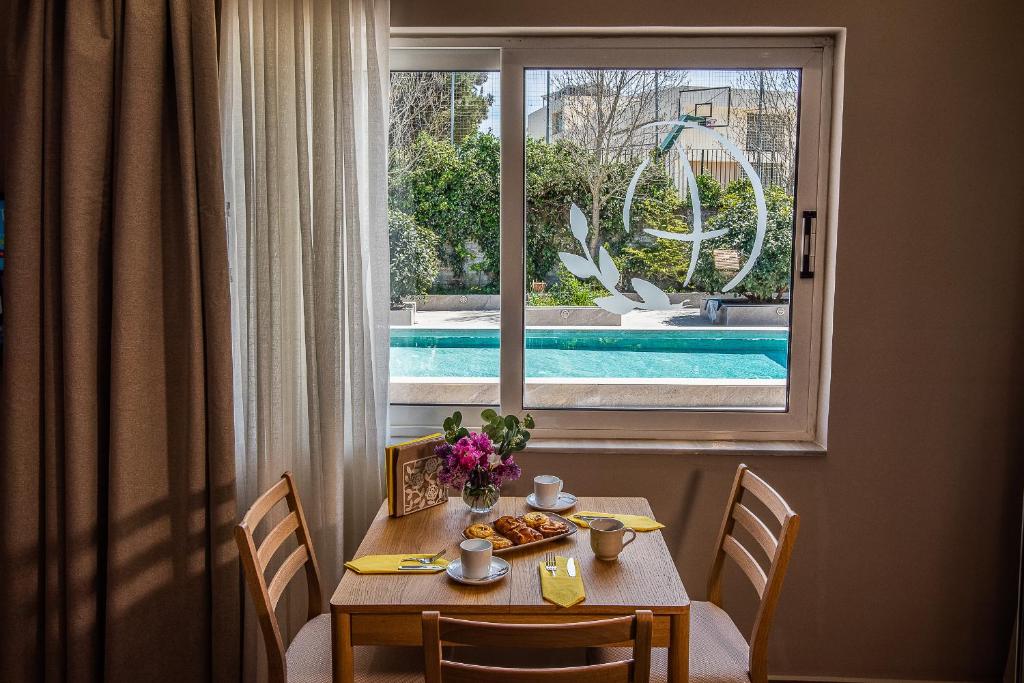 a table with a plate of food in front of a window at Ivy Residences with Pool in Ayía Varvára