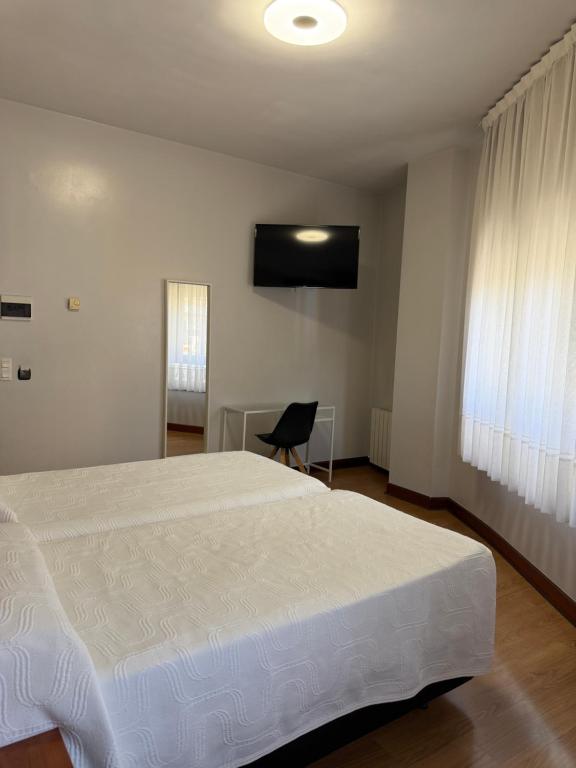 a bedroom with a large white bed and a chair at Pensión La Salve in Bilbao