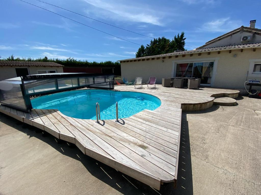 a swimming pool with a wooden deck next to a house at La maison multicolore in Livron-sur-Drôme