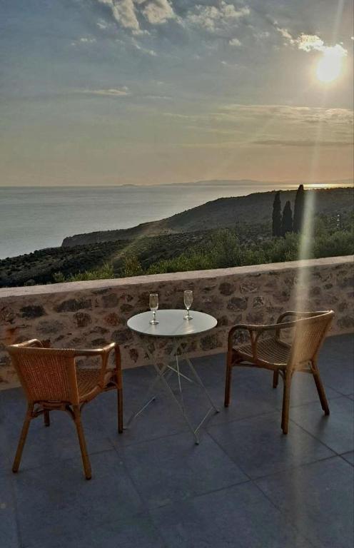 a table and chairs on a balcony with the ocean at Ελαιόλιθοι Μάνη Villas in Oitylo
