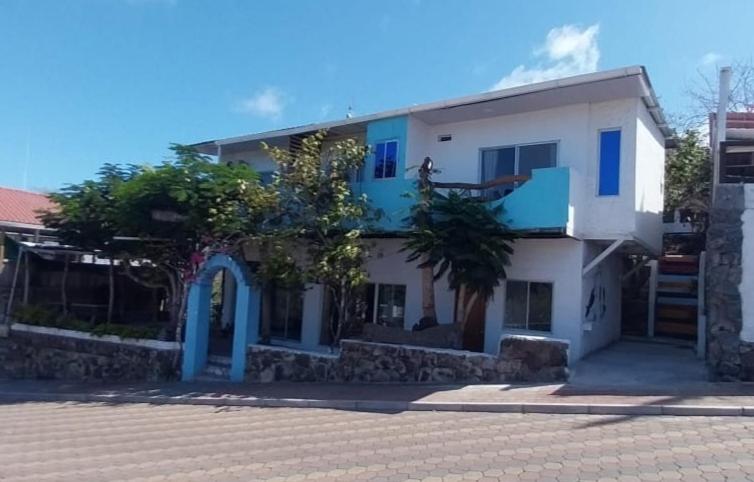a white house with blue trim on a street at Hostal Cabañas Don Jorge in Puerto Baquerizo Moreno