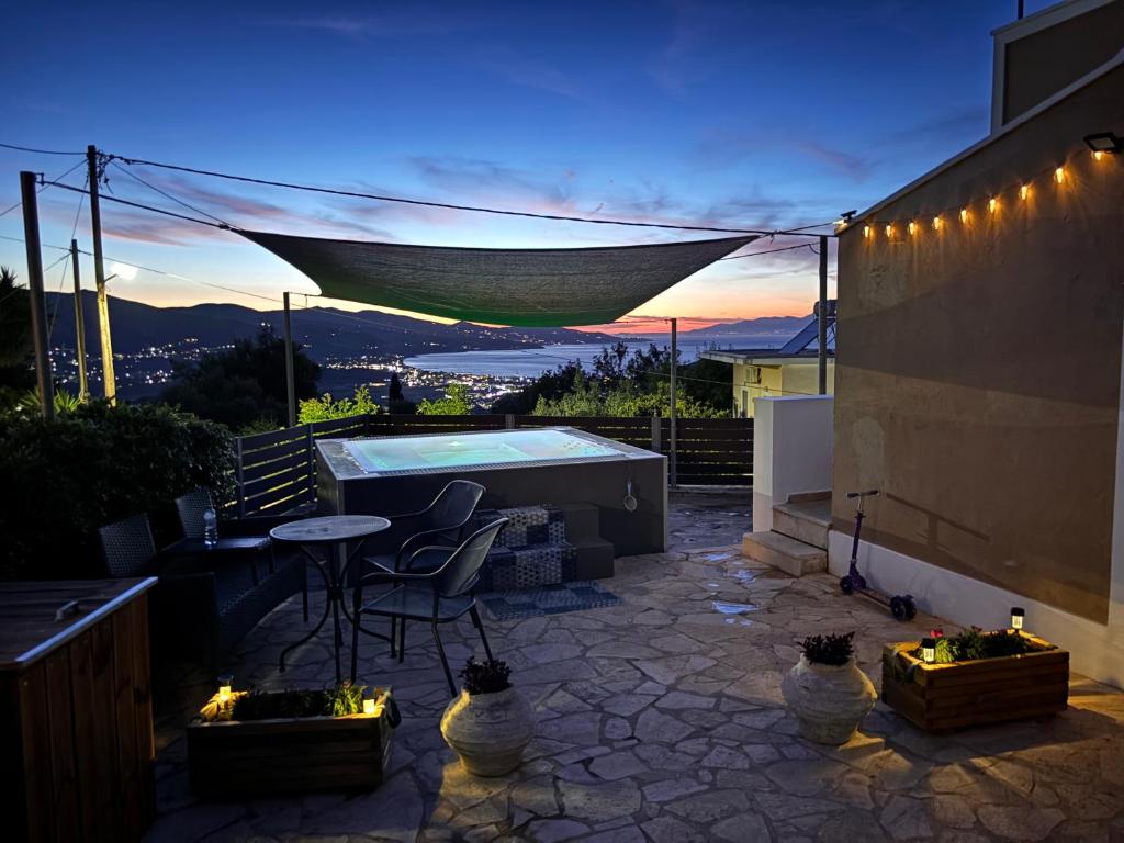 a patio with a hot tub and a table and chairs at Villa Thea - Τhe View 1st floor in Áno Yerakaríon