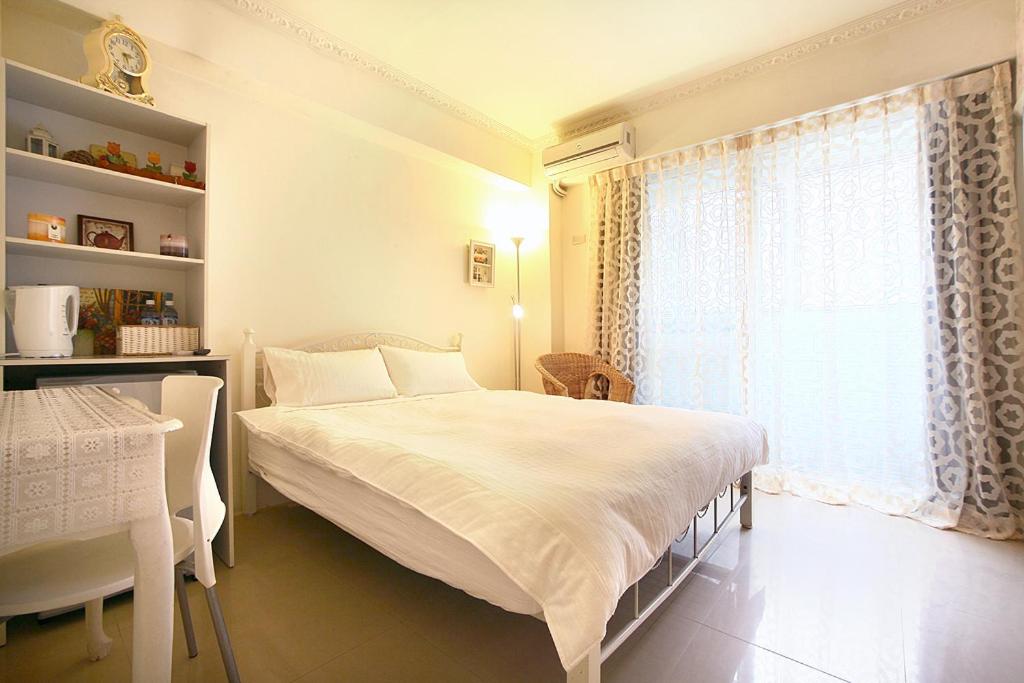 um quarto com uma cama branca e uma janela em RaRa Stay em Taichung
