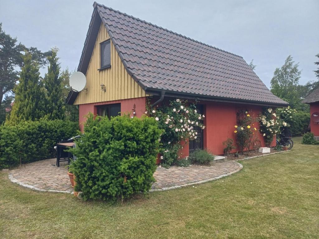 a red house with a black roof on a yard at Ferienhaus Rümdriewer in Pruchten