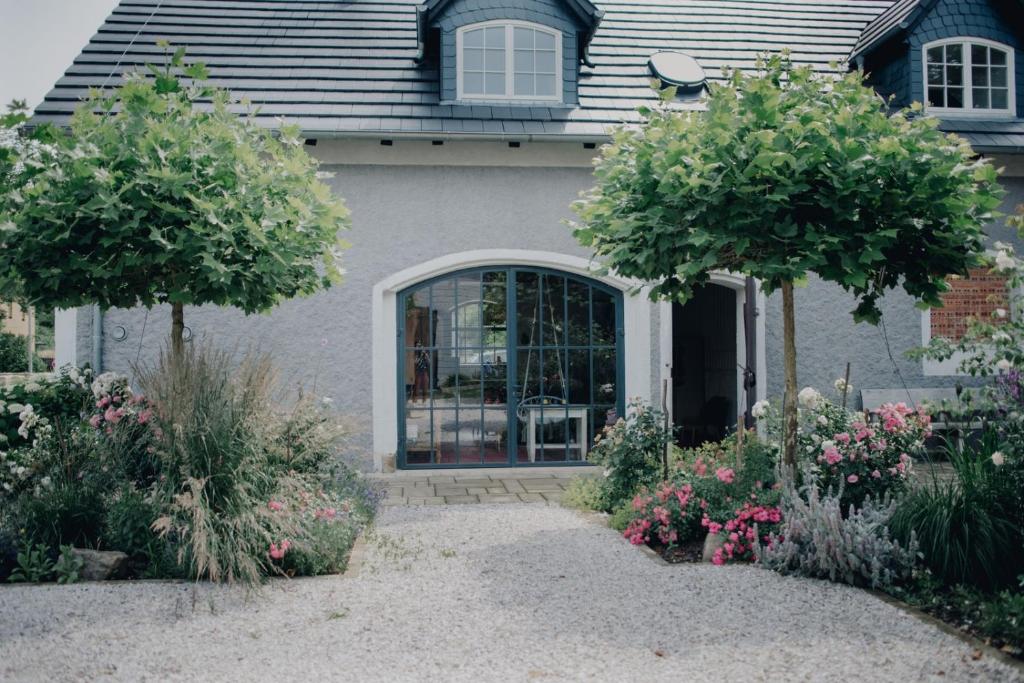 a house with two trees and flowers in front of it at Flowland Tarczyn in Tarczyn