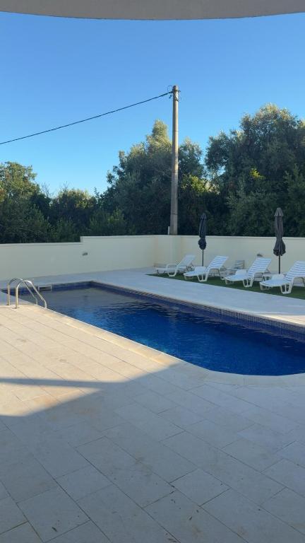 a swimming pool with white lounge chairs next to it at Swimming pool apartment in Budva