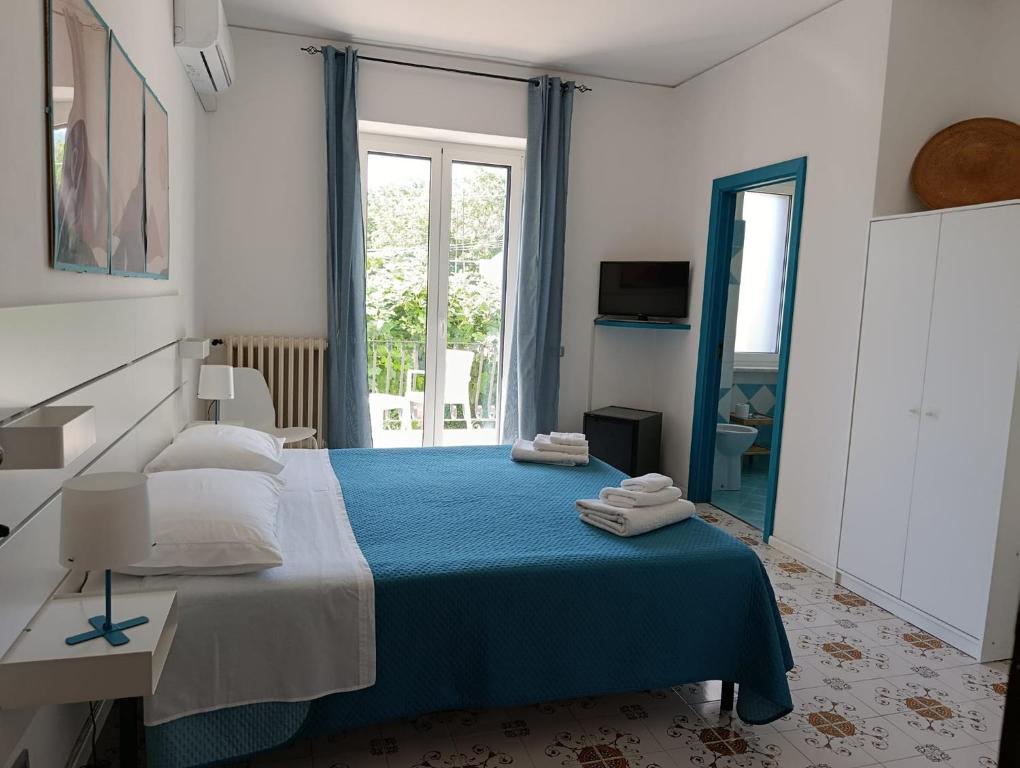 a bedroom with a bed with a blue blanket at Villa Rosa Rooms in Ischia Town