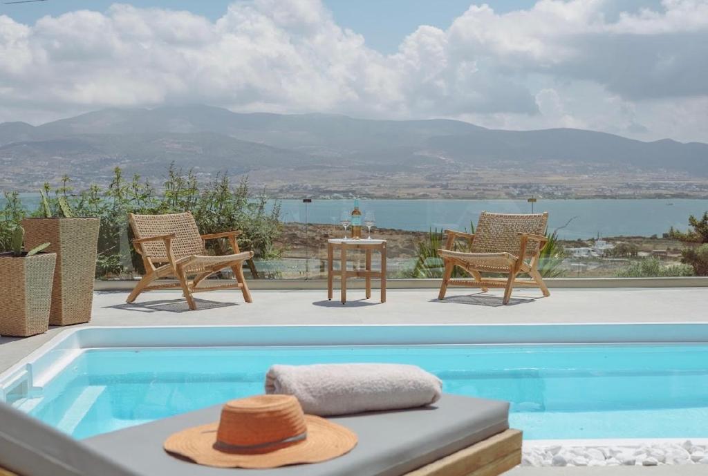 a pool with chairs and a table with a hat at Morning glow villa in Antiparos