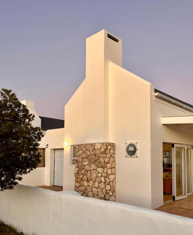 a white house with a stone wall at Fisherman's Rest in Paternoster