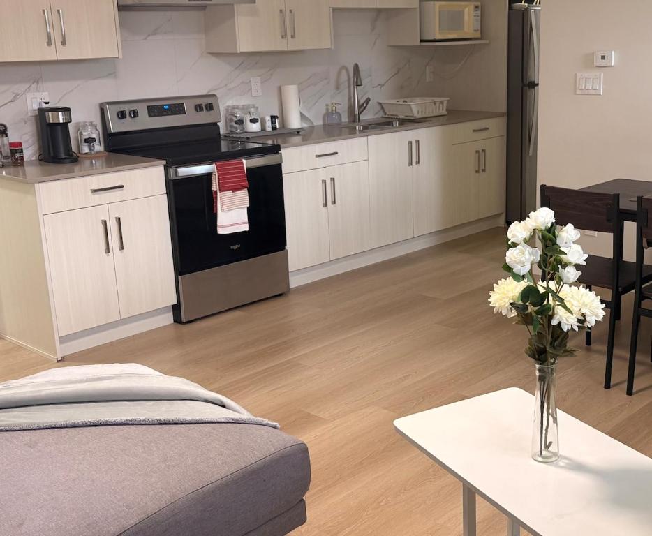 a kitchen with white cabinets and a vase of flowers on a table at Cozy home in Burnaby