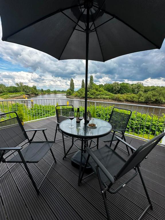 a table and chairs on a deck with an umbrella at Lesum View Apartment Bremen in Bremen
