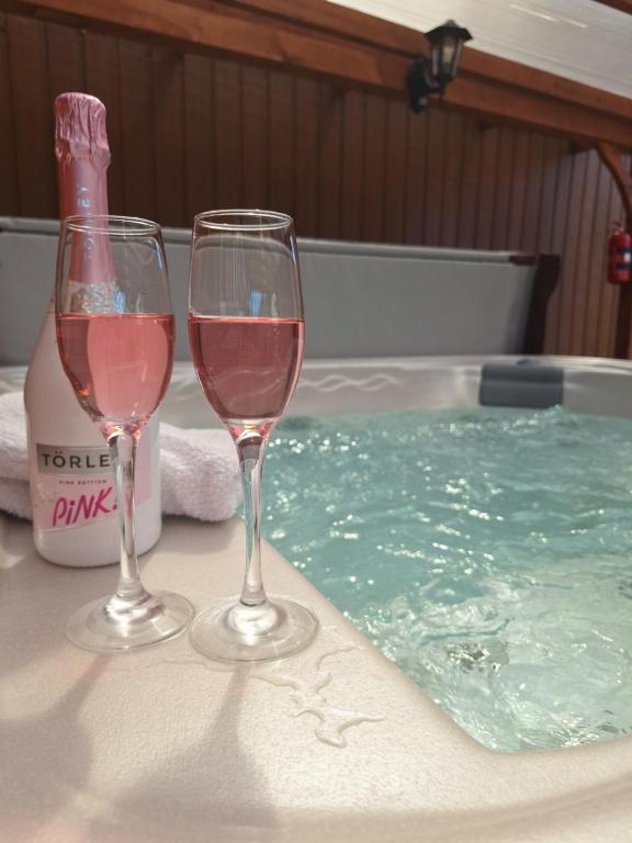 two glasses of wine sitting next to a swimming pool at Várfal apartman II in Eger