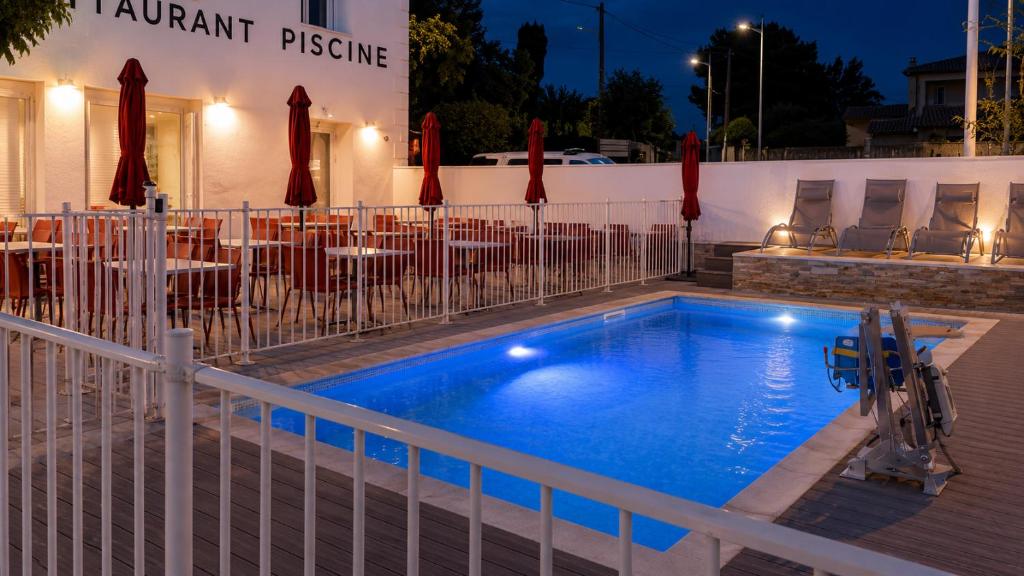 a swimming pool in front of a restaurant with a table at Rovotel - Le Rove in Le Rove