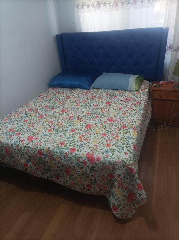 a bed with a blue head board with a floral bedspread at José Coro in La Serena
