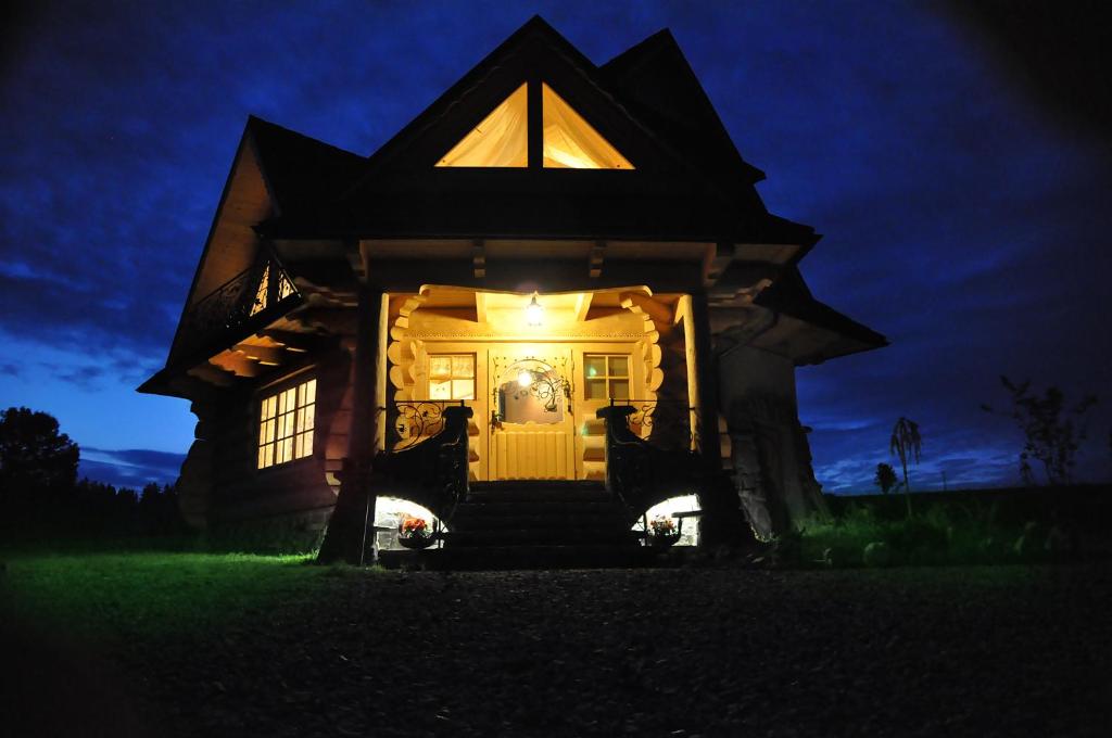 a house with a light on the door at night at U Zająca pod miedzą in Ciche