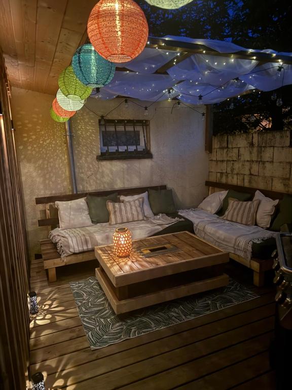 a patio with a couch and a table and a blue umbrella at Studio chaleureux, massage, terrasse privé, barbecue et balneo in Cussac-Fort-Medoc