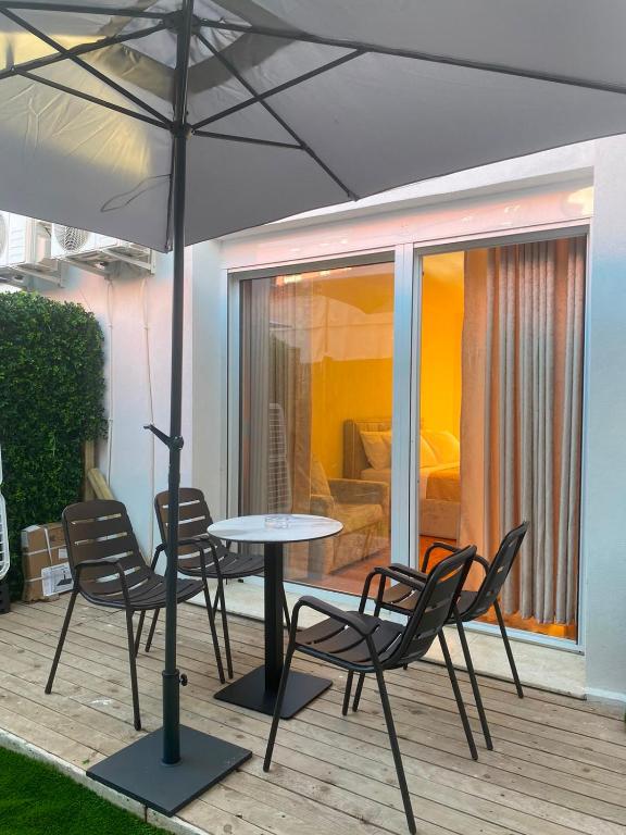 a table and chairs with an umbrella on a deck at Dina's Rooms Himara in Himare