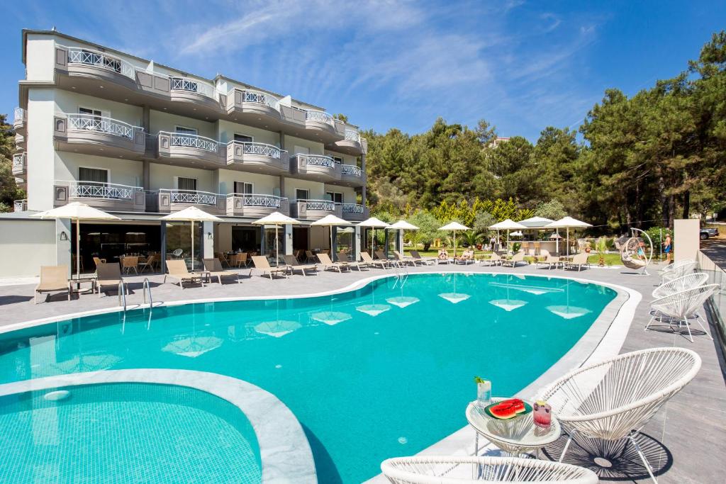 a resort pool with chairs and umbrellas at Green Bay in Limenaria