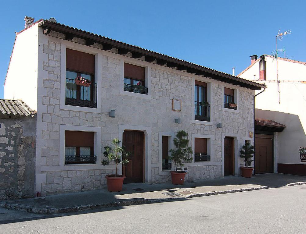 a white building with potted plants in front of it at Apartamentos Turísticos los Abuelos in Montemayor de Pililla