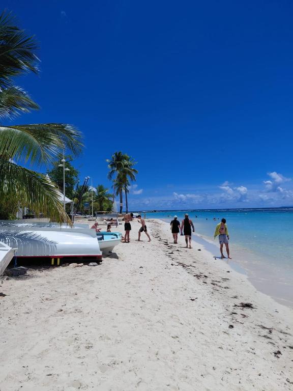 a group of people walking on a beach at Nid du Lagon in Sainte-Anne