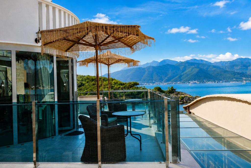 a balcony with a table and umbrellas overlooking the water at Luxury Sea Residence by Kristina in Tivat