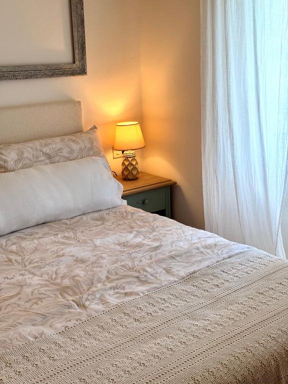 a bedroom with a bed and a lamp and a window at Casa Mirabel Laurel in Fene