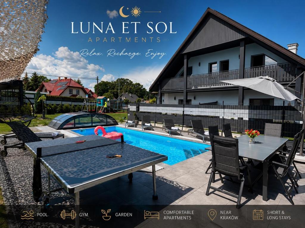 a ping pong table and chairs next to a swimming pool at Luna Et Sol Apartments in Rząska