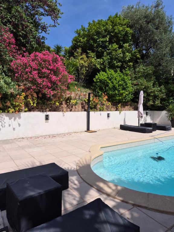 a swimming pool in a yard with pink flowers at Rez de villa avec piscine in Menton