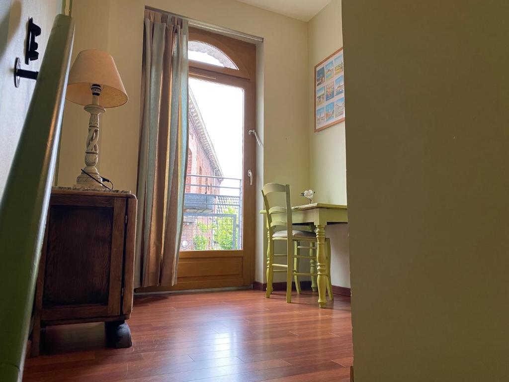 a room with a table and a desk with a window at La cour des hôtes in Fenain