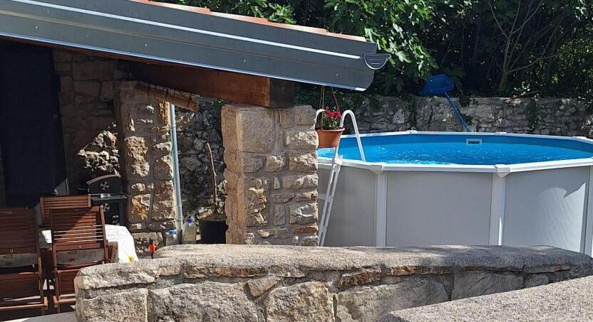 a hot tub in a backyard with a stone wall at House Casa Della Nonna in Kršan