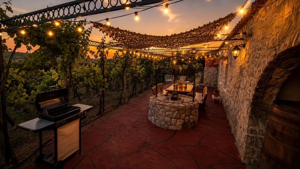 a wine cellar with a table and lights and grapes at Private Vineyard House in Banjol