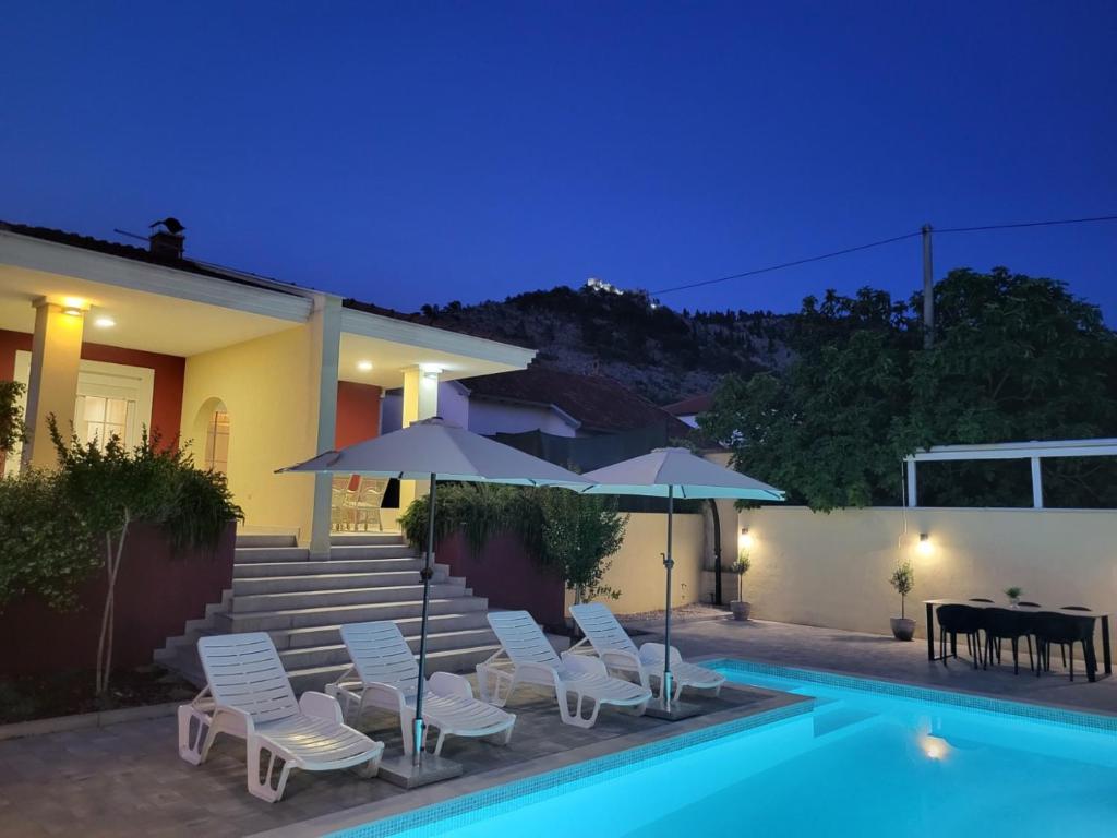 a house with a swimming pool with chairs and umbrellas at Villa Bona - Private Pool Oasis in Mostar