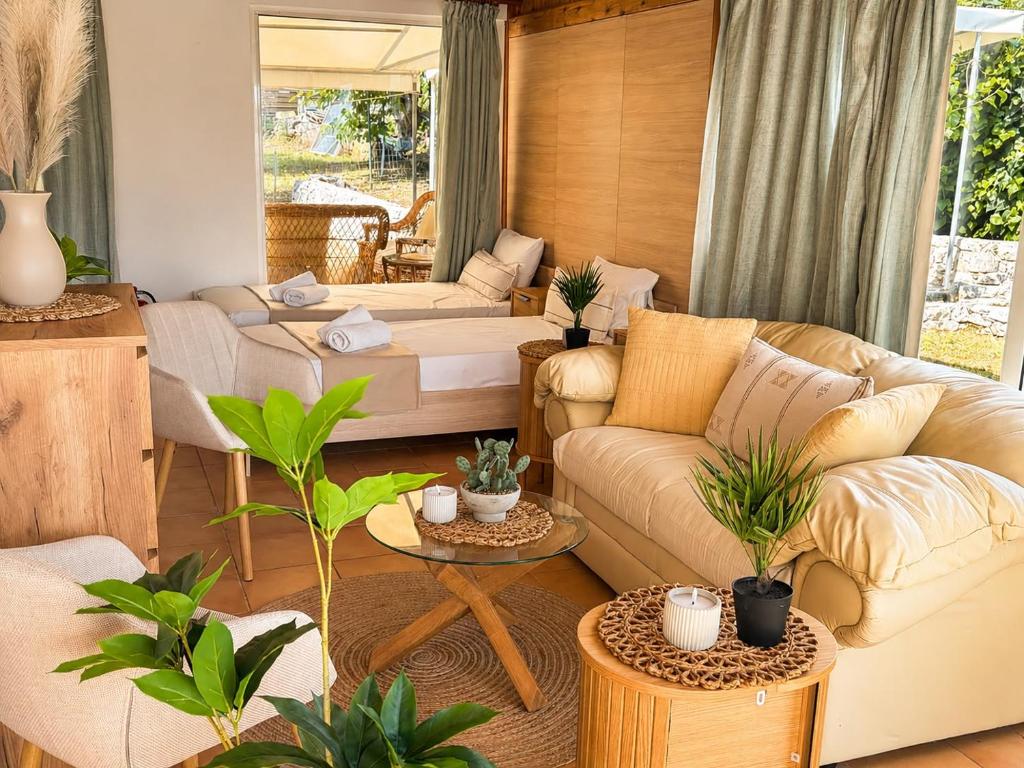 a living room with couches and potted plants at KATIA BEACH Holiday Cottage in Kassiopi