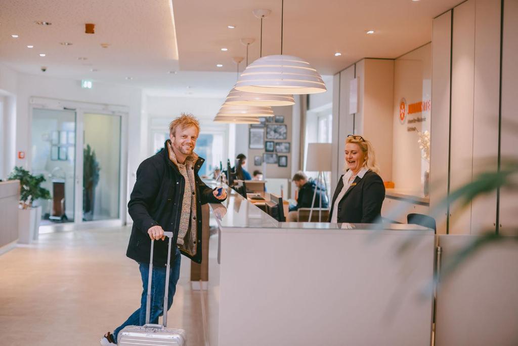 a man with a suitcase in an office with a woman at Johanniter Gästehaus in Münster