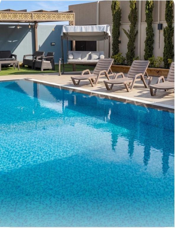 a swimming pool with two chairs and a bed at The Mountain View in Ash Shāghūr