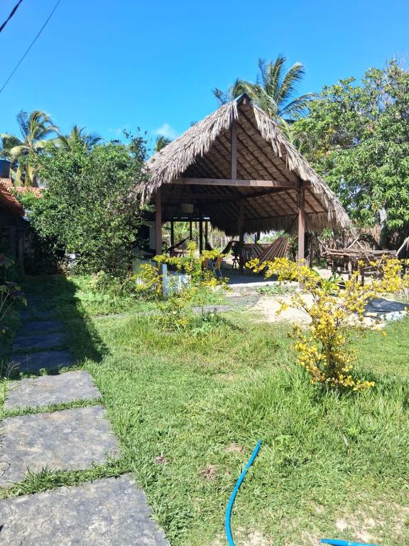 a house with a thatched roof in the grass at Bicho Grilo Hostel in Atins