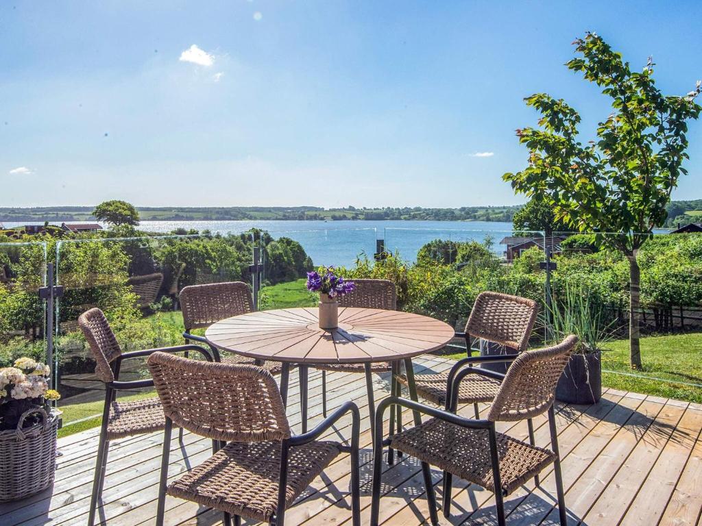 a table and chairs on a deck with a view of the water at 5 star holiday home in Kolding in Kolding