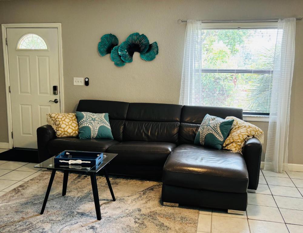 a living room with a leather couch and a table at Sunshine Acre 2B 2B King Master Suite, BIG Yard in Davie