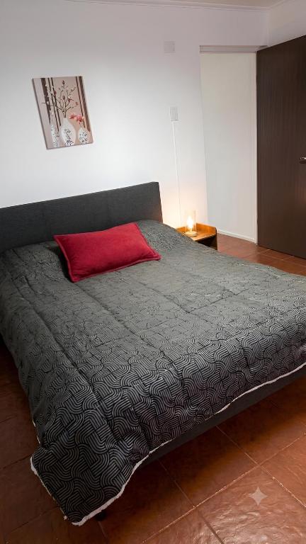 a bed with a red pillow on top of it at Dpto céntrico en primer piso in Valdivia