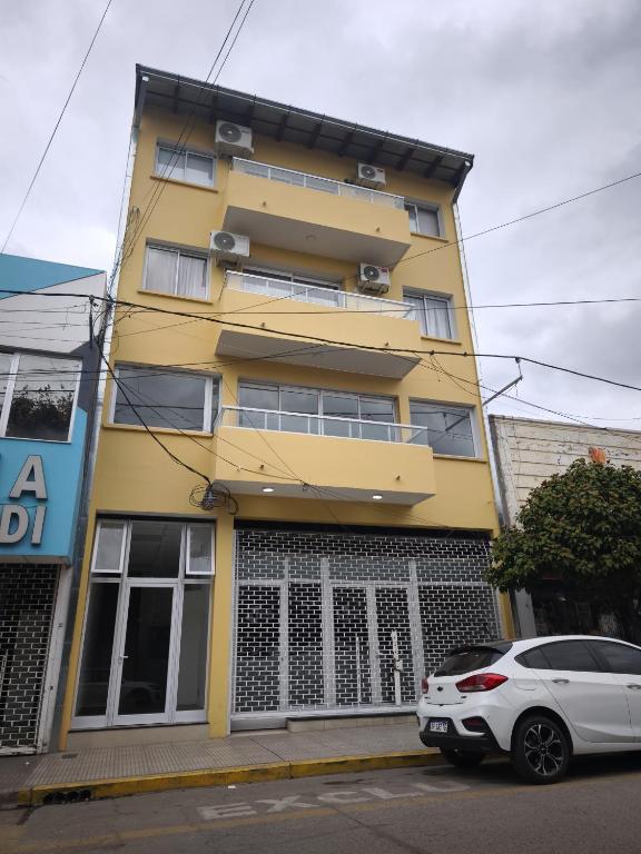 a yellow building with a car parked in front of it at Departamento Alberdi in San Pedro de Jujuy